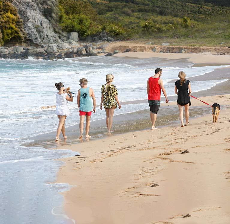 A family and a dog walking on a beach of St. Kitts