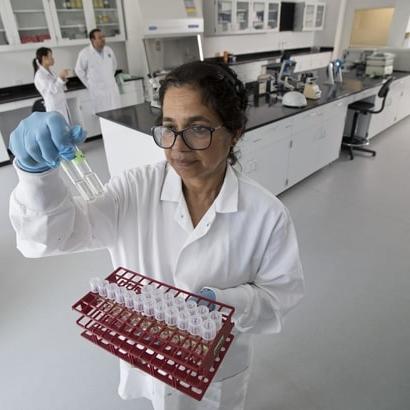 A lab technician holding up a sample of liquid