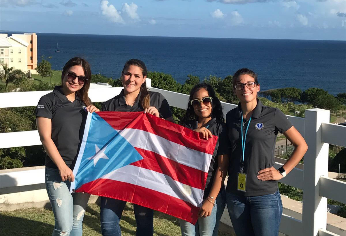 Students posing with a Puerto Rican flag overlooking the coast
