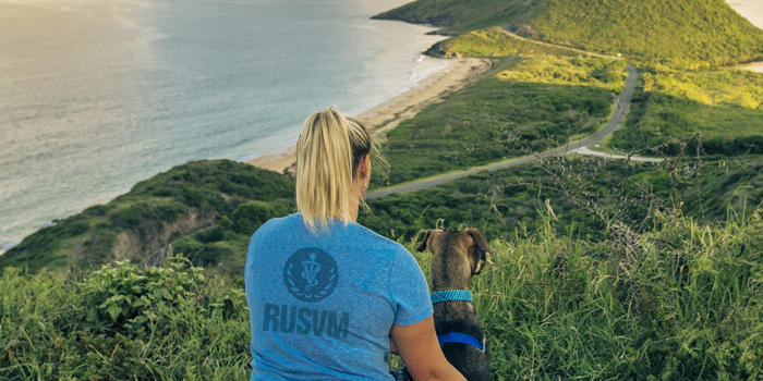Women and dog on hill overlooking ocean