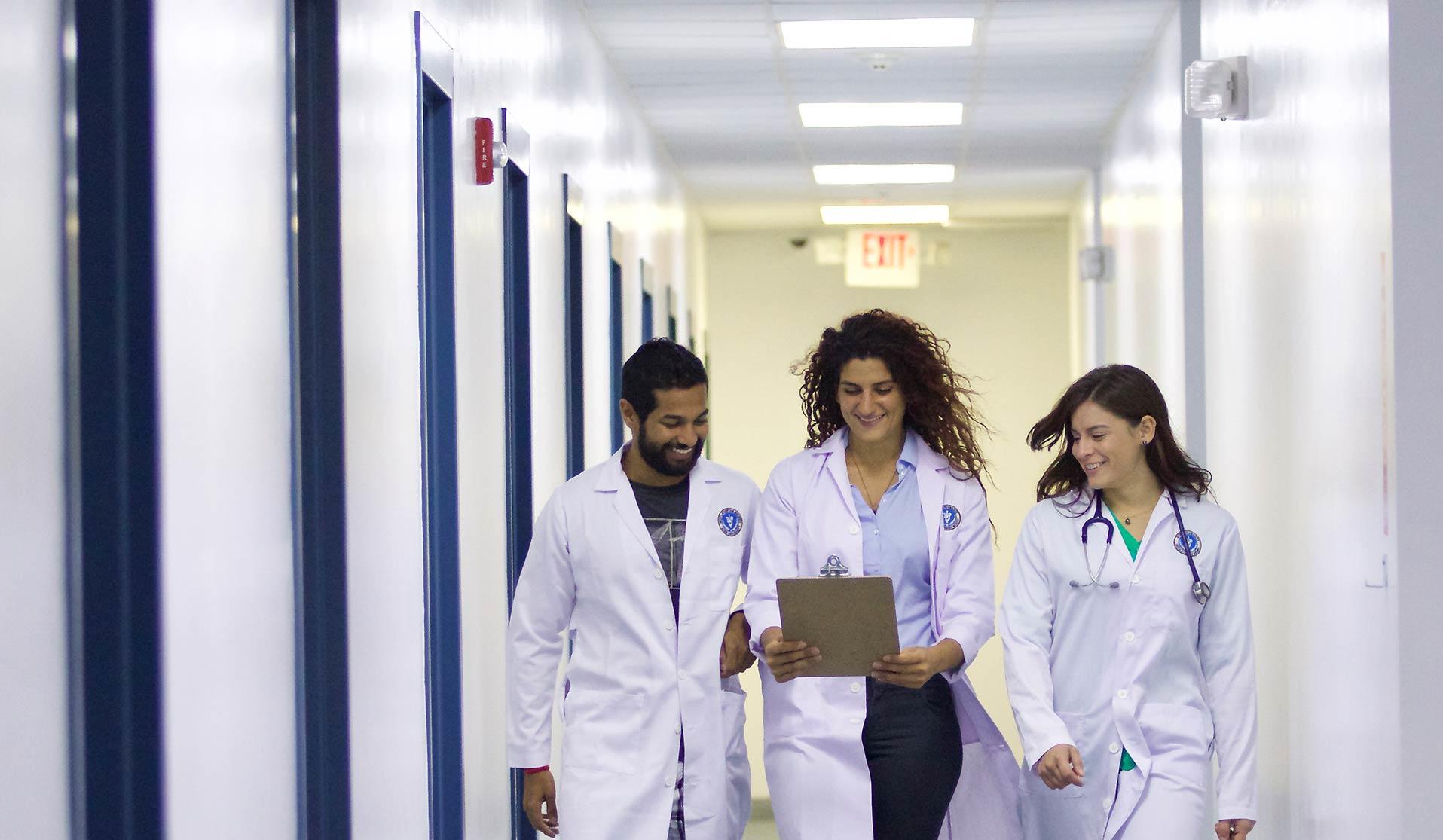 Three veterinarian students laughing and walking down a hallway