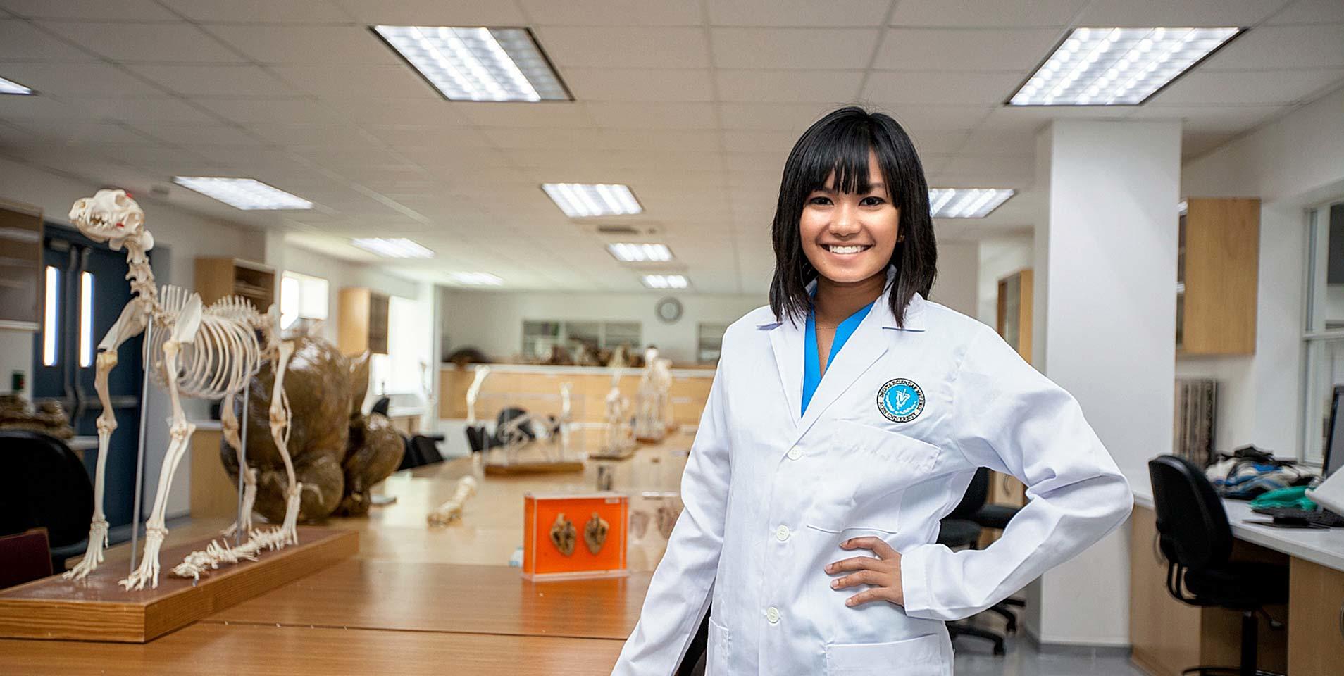 Female veterinarian posing next to an animal skeleton in a classroom
