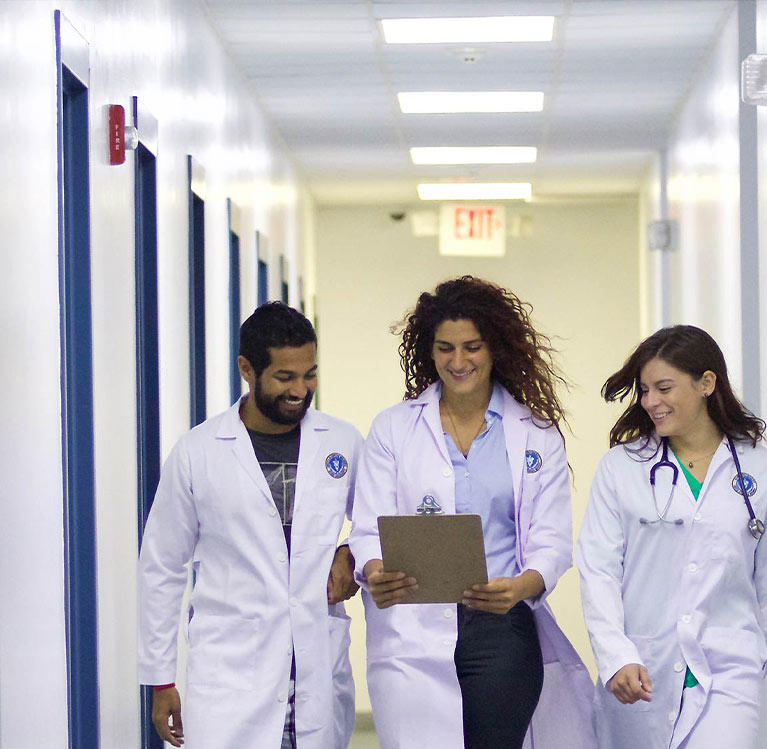 Three veterinarian students laughing and walking down a hallway