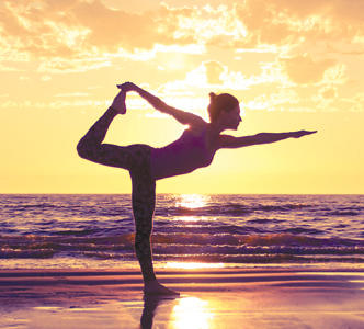 A woman does yoga by the beach