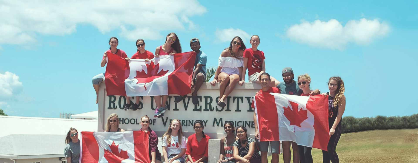 Students on a sign holding canadian flags