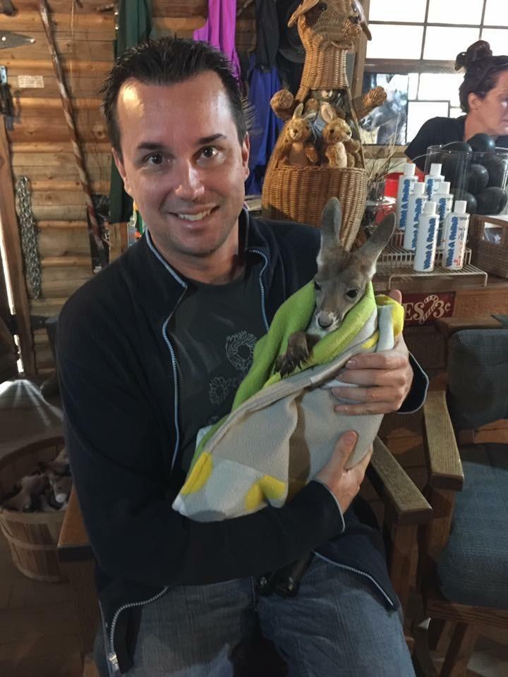 Man holding a small kangaroo wrapped in a towel