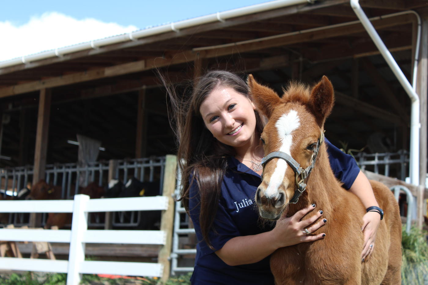 Student posing with her arms around a baby horse